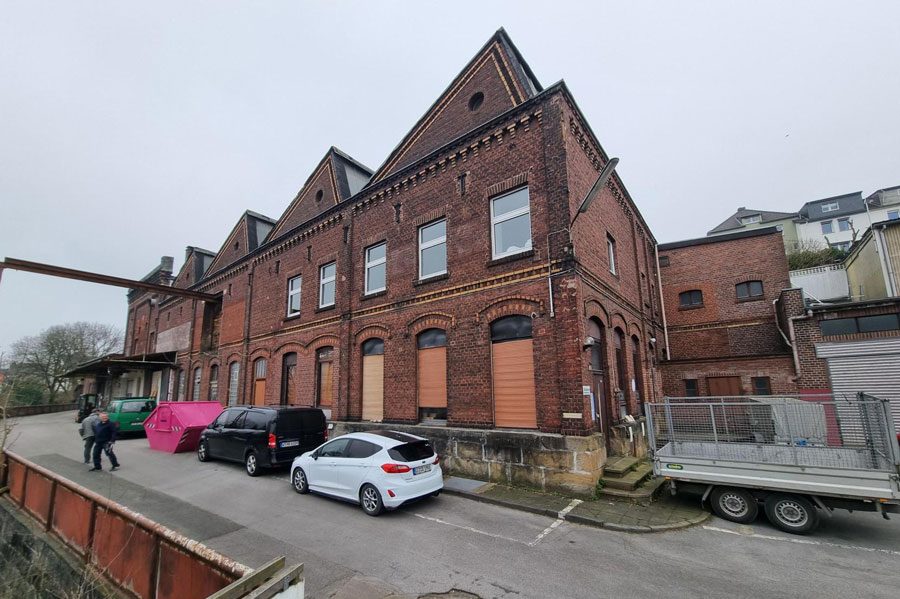 Moderner Wohnbau mit Holzverkleidung und großen Fenstern, umgeben von Grünflächen.